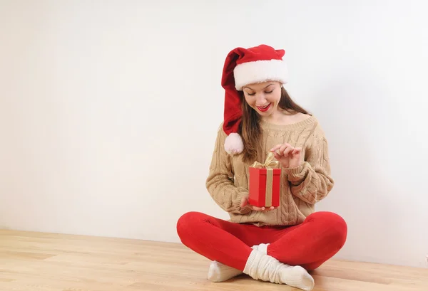 Carino giovane donna in cappello di Babbo Natale con scatola regalo in mano — Foto Stock