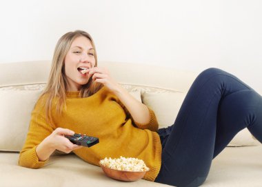 TV izlerken, evde kanepede rahatlatıcı güzel genç kadın