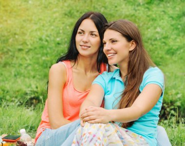 Parkta piknik üzerinde iki mutlu gülümseyen kadın arkadaşlar 