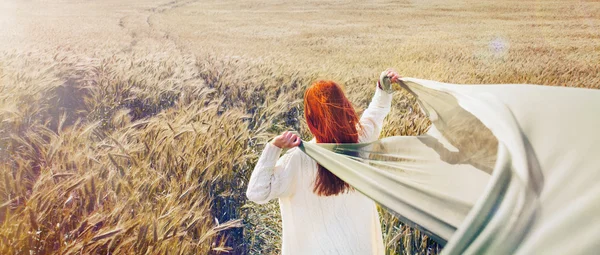 Panoramabild einer wandernden Frau mit roten Haaren durch das flache Feld — Stockfoto