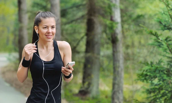 Estilo de vida saludable fitness mujer deportiva con auriculares trotando en —  Fotos de Stock