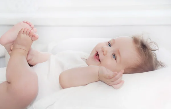 Pequeño bebé feliz sano que miente en la almohada blanca suave — Foto de Stock