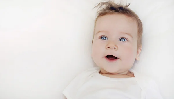 Portrait of happy baby boy lying on soft white pillow — Stock Photo, Image