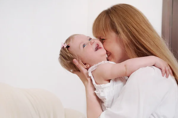 Mãe e seu bebê pequeno bonito menina se divertindo no sofá em h — Fotografia de Stock