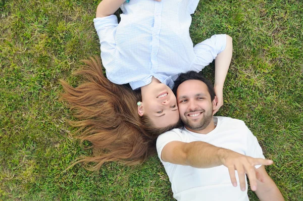 Jeune couple couché sur l'herbe dans le parc — Photo