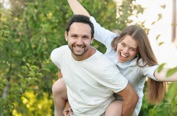 Ungt par har det sjovt i haven ved deres hus - Stock-foto