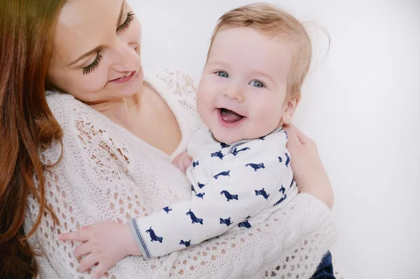 Lachende gelukkig babyjongen met zijn zorgzame moeder — Stockfoto