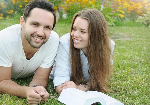 Couple of young students reading a book together in the park — Stock Photo, Image