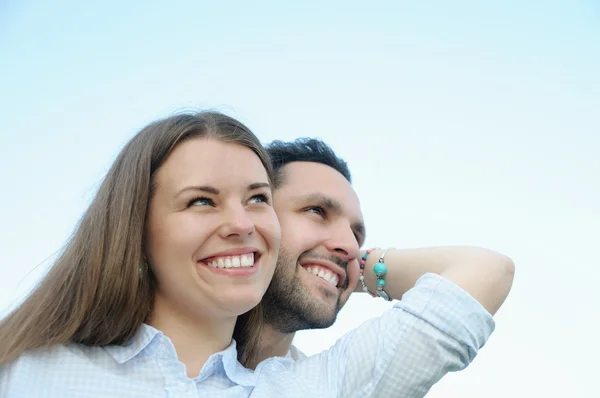 Happy young couple looking in one direction outdoors on blue sky — Stock Photo, Image