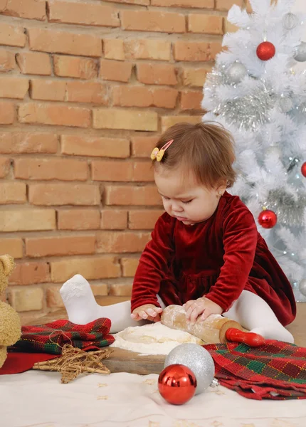 Mała dziewczynka w czerwonej sukience Dokonywanie ciasteczek na święta — Zdjęcie stockowe