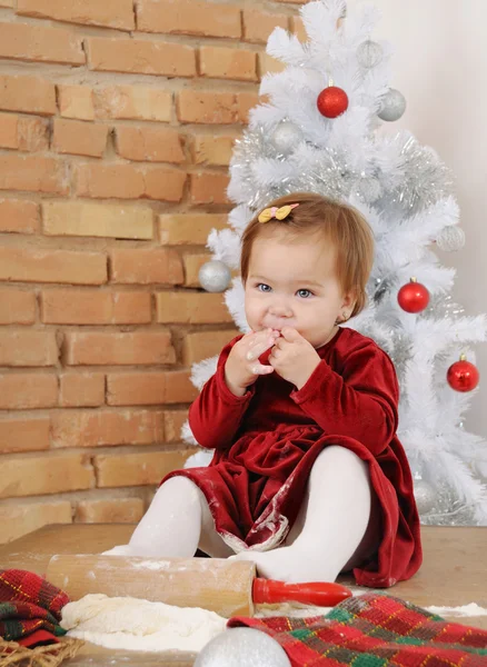 Cute little baby girl with big blue eyes trying pastry for Chris Stock Photo