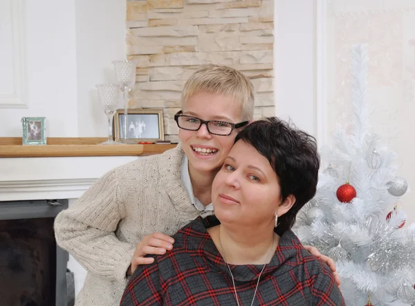 Lycklig pojke med sin vackra mor nära brasan i julafton — Stockfoto