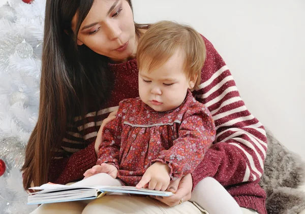 Portret ładny małą córeczkę, czytanie książki z jej matka n — Zdjęcie stockowe