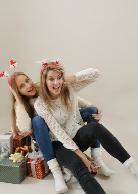 two beautiful girls having fun on old vintage sled with gifts fo