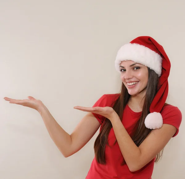 Beautiful young woman in Santa hat advertise and show an ampty p — Zdjęcie stockowe