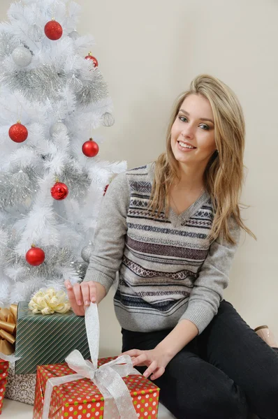 Una atractiva joven abre un regalo en la mañana de Navidad —  Fotos de Stock