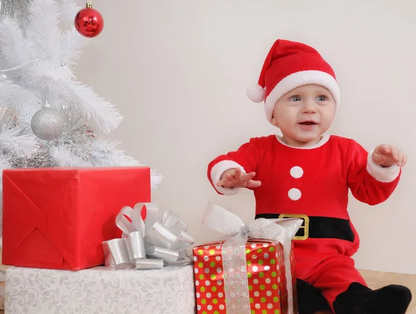 Ładny szczęśliwy małego chłopca w garnitur Santa z darów w pobliżu Christm — Zdjęcie stockowe