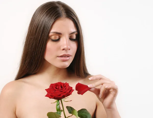 Cute beautiful woman tears off petals of red rose on white backg — Stock Photo, Image