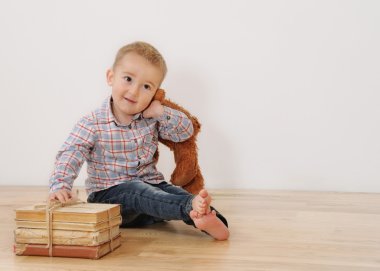 studio shot of little smiling boy with his toy and books