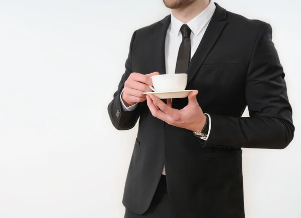 Homem de negócios lado do corpo em terno preto com xícara de café em branco — Fotografia de Stock