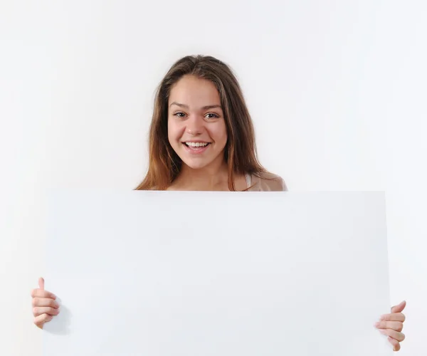 Beautiful young woman holding a placard and smiling against a wh — ストック写真