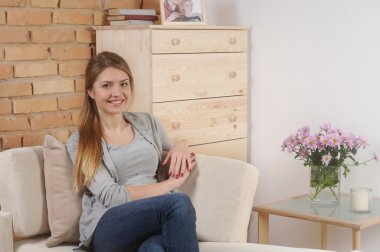 attractive smiling young woman siting on sofa at home