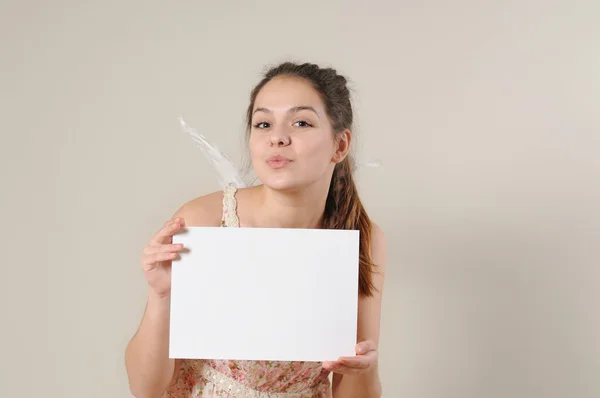 Cute angel girl blowing a kiss and holding a blank placard — ストック写真