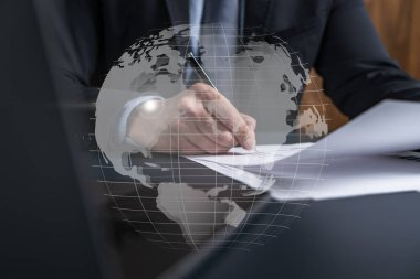 Takım elbiseli iş adamı kontrat imzaladı. Dünya haritası hologramıyla çift pozlama. Uluslararası iş anlaşması imzalayan adam.