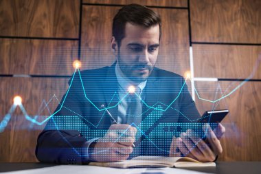 Ofisteki bir işadamı telefon ve stok grafiği kullanarak notlar alıyor. Çoklu maruz kalma. Resmi giysi.