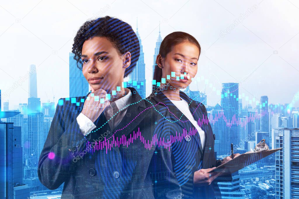 Two young attractive businesswoman in suits pondering about new venture capital and hi-tech start up and try to forecast risks and estimate prospective earning growth. Hologram chart on Kuala Lumpur.