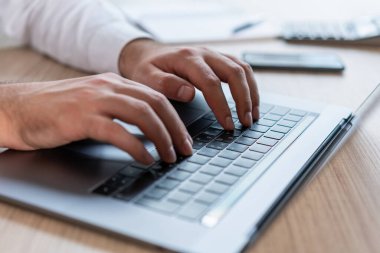 Erkek el ofis yöneticisinin dizüstü bilgisayarda yazı yazışının üst görüntüsü, siyah klavyede ellerin yakın çekimi. Ofis sekreteri bilgisayarla çalışıyor, yüzü yok. İş kavramı