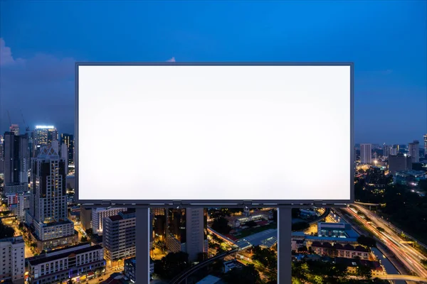 Blanco wit wegreclamebord met KL stadsgezicht achtergrond 's nachts. Reclameposter, model, 3D-weergave. Vooraanzicht. Het concept van marketing communicatie om ideeën te promoten of te verkopen. — Stockfoto