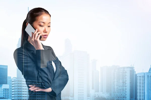 Процветающая удивительная молодая азиатская деловая женщина в костюме задумчиво говорящая по телефону, город Куала-Лумпур. Концепция консультантов как решателей проблем. Небоскрёбы КЛ. Двойное воздействие. — стоковое фото