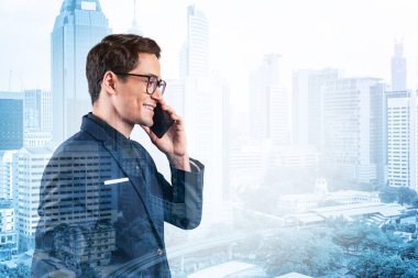 Takım elbiseli, gözlüklü, telefonla konuşan ve Kuala Lumpur şehri manzarasına bakan başarılı yakışıklı girişimci. Sorun çözme danışmanlığı kavramı. KL gökdelenleri. Çift pozlama.