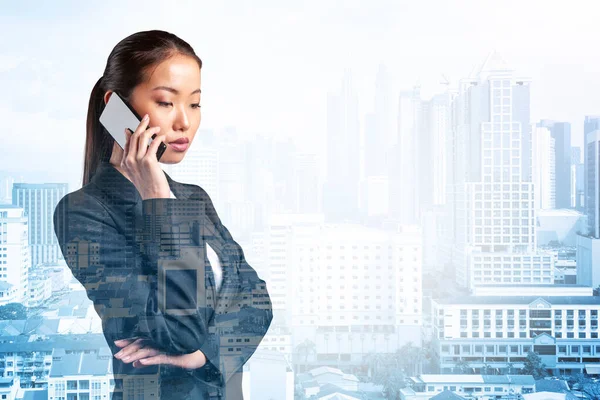 Процветающая удивительная молодая азиатская деловая женщина в костюме задумчиво говорящая по телефону, город Куала-Лумпур. Концепция консультантов как решателей проблем. Небоскрёбы КЛ. Двойное воздействие. — стоковое фото
