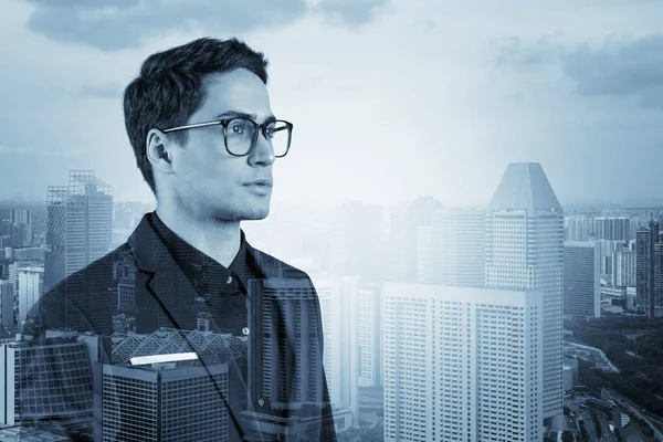 Joven hombre de negocios guapo en traje y gafas soñando con nuevas oportunidades de carrera después de la graduación del MBA. Singapur en segundo plano. Doble exposición. — Foto de Stock