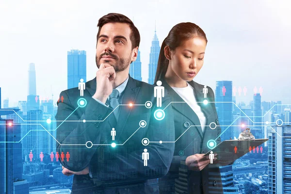 Businessman and businesswoman as a SMM specialists thinking about development of social media marketing strategy to achieve business goals. Hologram icons over Kuala Lumpur background. — Stock Photo, Image