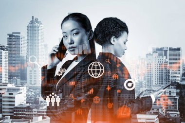 Takım elbiseli iki hayret verici genç iş kadını araştırma ve geliştirme departmanındaki sorunları çözmek için yeni teknik yaklaşımlar bulmaya çalışıyor. Bangkok arka planında Fintech hologram simgeleri.