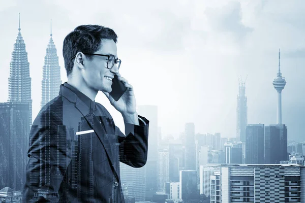 Чудовий підприємець в костюмі і келихи задумливо розмовляє по телефону і дивиться на Куала-Лумпур. Концепція вирішення проблем консалтингу. KL skyscrapers Подвійний вплив. — стокове фото