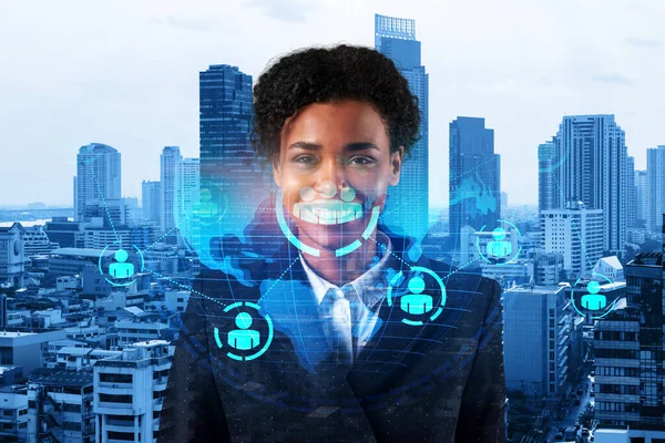 Smiling black woman HR director at international company is thinking about recruitment of highly qualified specialists. Women in business concept. Social media hologram icons over Bangkok.