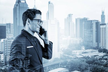 Takım elbiseli, gözlüklü, telefonla konuşan ve Kuala Lumpur şehri manzarasına bakan başarılı yakışıklı girişimci. Sorun çözme danışmanlığı kavramı. KL gökdelenleri. Çift pozlama.
