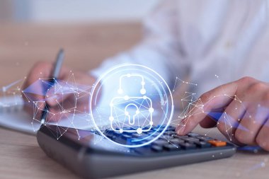 Bir iş adamı, hesap makinesi kullanarak siber güvenlik korumasında risk olasılığını hesaplıyor. Çalışma masasının üzerine asma kilit hologramı simgeleri. Resmi giysi.