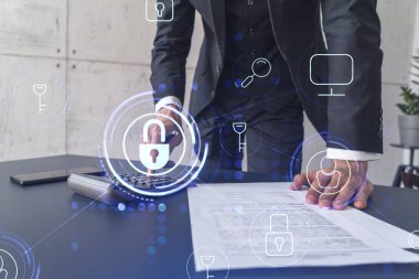 Bir iş adamı, hesap makinesi kullanarak siber güvenlik korumasında risk olasılığını hesaplıyor. Çalışma masasının üzerine asma kilit hologramı simgeleri. Resmi giysi.