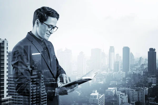 Joven hombre de negocios guapo en traje y gafas pensando en cómo abordar el problema, nuevas oportunidades de carrera, asignación de MBA. Bangkok en el fondo. Doble exposición. — Foto de Stock