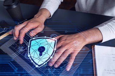 Bir programcı bir siber güvenliği bilgisayar korsanlarından korumak ve müşterilerin gizli bilgilerini kaydetmek için klavyeye kod yazıyor. Yazan ellerin üzerine asma kilit hologramı simgeleri.