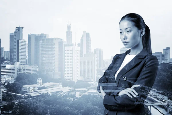 Процветающая азиатская бизнесвумен в костюме со скрещенными руками. Город Куала-Лумпур. Концепция женщины в бизнесе. Небоскрёбы КЛ. Двойное воздействие. — стоковое фото
