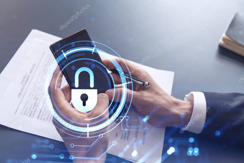 A businessman in formal wear reading the contract to prevent probability of risks in cyber security and checking details in the phone. Padlock Hologram icons over the working desk.