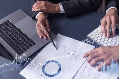 Borsa davranışlarını tahmin etmek için tarihi verileri araştıran iki tüccar ve kadın. İnternet ticareti konsepti. Belgelerin olduğu masanın üzerinde eski ve finansal hologram şeması