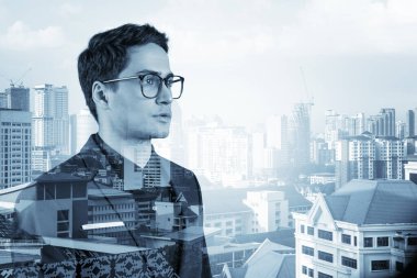 Takım elbiseli ve gözlüklü genç yakışıklı işadamı MBA mezuniyetinden sonra yeni kariyer fırsatları hayal ediyor. Kuala Lumpur arka planda. Çift pozlama.