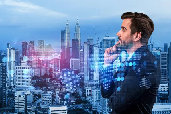 Handsome Caucasian HR director at international company is thinking about efficient strategy to recruit highly qualified specialists. Social media marketing hologram icons over Kuala Lumpur background